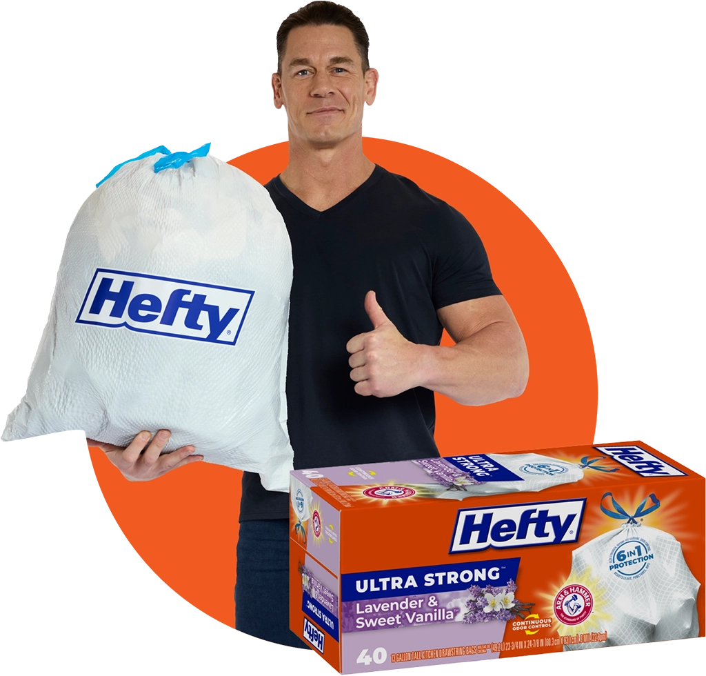 John Cena smiles holding a Hefty trash bag and gives a thumbs up. Below Cena is a box of Hefty Ultra Strong trash bags